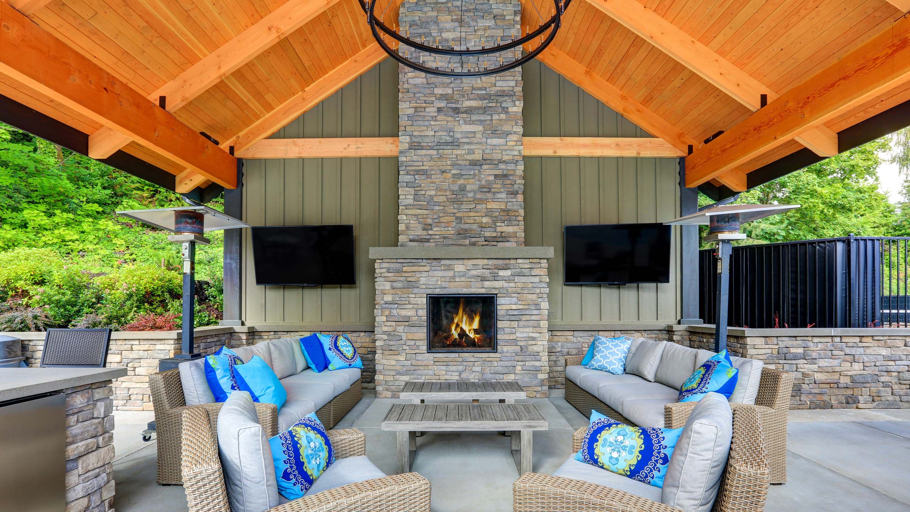 sidewalled outdoor covered porch with furniture and tvs